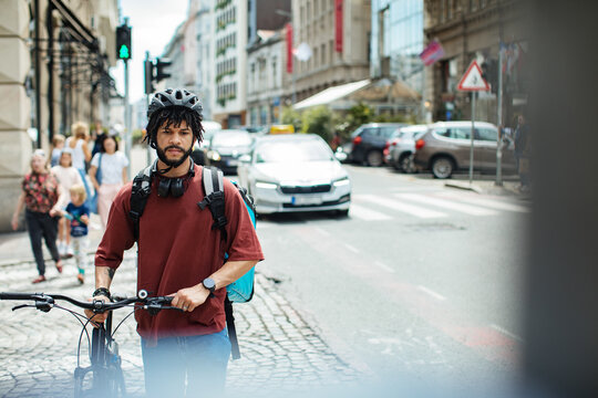 Delivery man with large backpack riding bicycle in urban setting