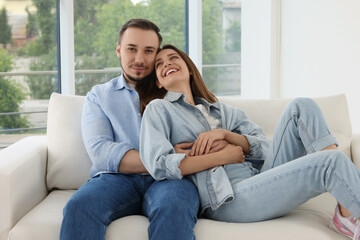 Obraz premium Man hugging his happy girlfriend on sofa at home