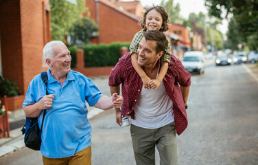 Three generations of family men walking and laughing together outdoors