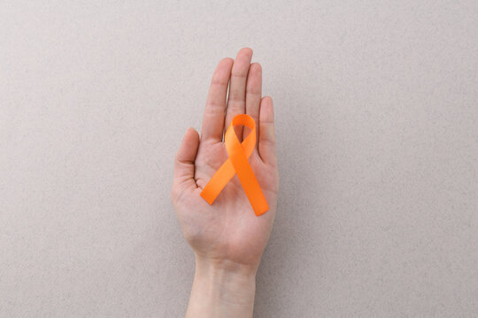 Woman with orange awareness ribbon on gray background, top view