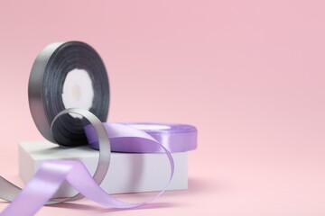 Ribbon reels in different colors on pink background, closeup. Space for text