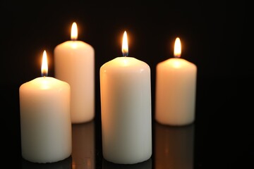 Many burning candles on mirror surface against black background