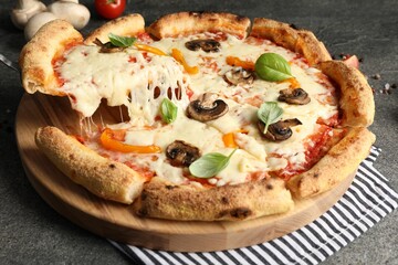 Taking piece of delicious vegetarian pizza at grey table, closeup