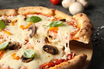 Taking piece of delicious vegetarian pizza at table, closeup