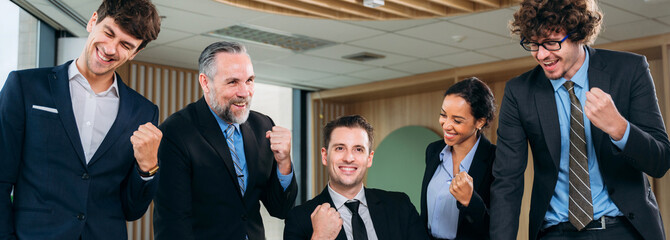 A group of business in suits are celebrating a victory.