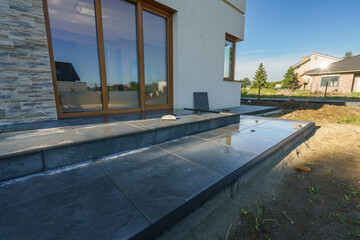 Ceramic terrace tiles on adjustable supports under construction. Elevated exterior floor build covered with water