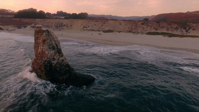 Rocky cliff, rocky island and sandy beach at sunset. Davenport Beach, Santa Cruz, California, United States of America.