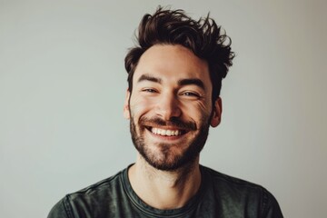 Obraz premium Portrait of a happy young man with a beard on a gray background