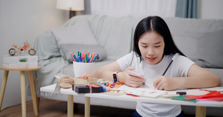 Portrait of Young Asian woman sitting on the floor uses a mobile phone to search for ideas for greeting cards. Holiday hobbies, crafts, DIY cards