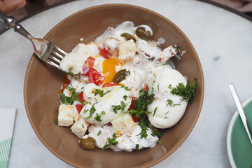 Enjoy a delightful dish of fresh poached eggs with vegetables and feta cheese served in a bowl