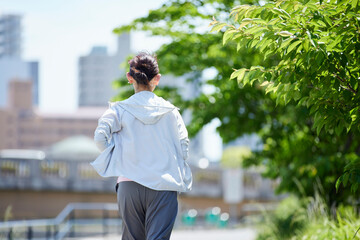 春の新緑の中ランニングを楽しむスポーツウェアをきたシニア女性