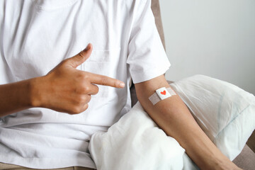 Young man pointing to his arm with plaster. Volunteer at the blood donation center.