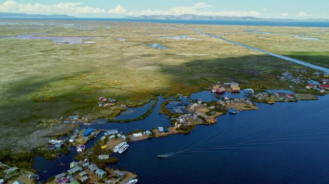 Panoramic aerial orbit above Uros Island floating homes on Lake Titicaca as cloud shadow passes over