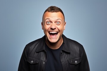 Man with leather jacket and surprised facial expression over blue studio background.