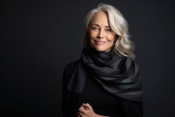 Portrait of a beautiful senior woman wearing scarf over dark background.