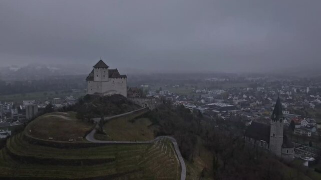 A slowly rotating aerial view of Gutenberg Castle and St. Nicholas Church in Balzers, panning slightly to the right.