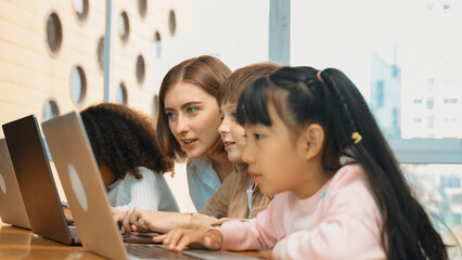 Smart teacher teaching and looking student using laptop at classroom. Professional instructor...
