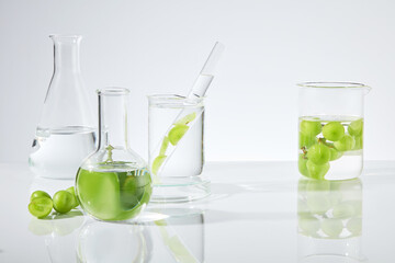 Plenty lab instruments displayed on white background, containing fresh grape and transparent liquid in. Empty space for product displaying, front angle shot