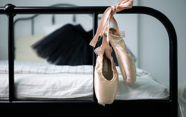 Ballet shoes hanging at the end of the bed and black ballet dress on the bed, Prepared for a girl...