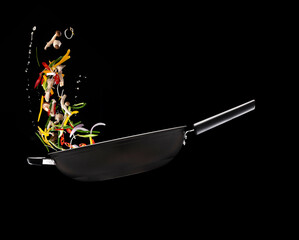 어두운 배경에 윅질을 해서 여러가지 야채가 섞이고 있다.