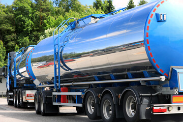 Rear view detail of a parked blue truck with clear tank trailers.