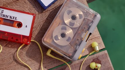 cassette tape record player vintage old school music release playing on wooden pier with water in background and bright colour 