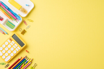 Colorful school supplies including pencils, calculator, and paper clips arranged on a vibrant yellow background