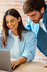 Happy young couple having loving relationships smile at home desk shopping online in online store. Young friendly couple in love look at computer screen planning travel choosing tour on vacation