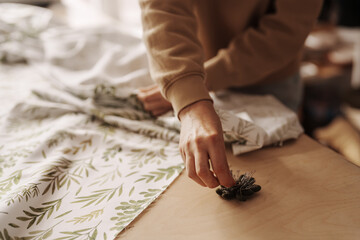 Close-up of a woman's hands working with fabric and pins in a sewing studio.