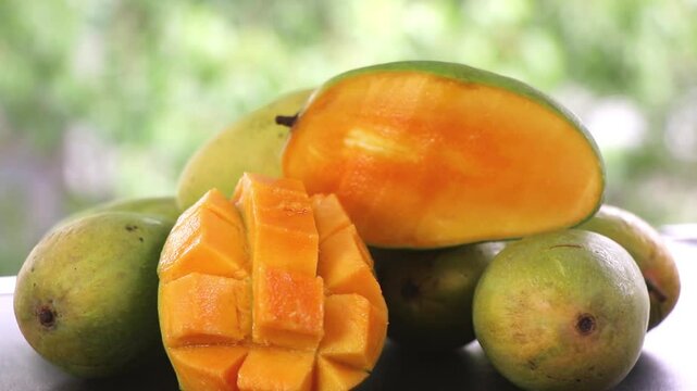 Footage of sliced ripen mango with a green natural background.