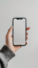 A hand holding a smartphone with a blank screen, perfect for app mockups or product presentations, set against a plain background.

