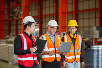 Metal steel sheets factory manager and employees inspecting products inside factory. Metalwork manufacturing Team professional walking training work for employees. Check quality of work with laptop.