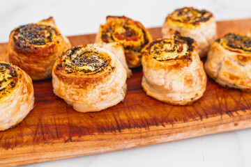 pumpkin spinach and cheese pastry rolls on wooden cutting board, freshly baekd and homemade,