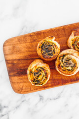 pumpkin spinach and cheese pastry rolls on wooden cutting board, freshly baekd and homemade,