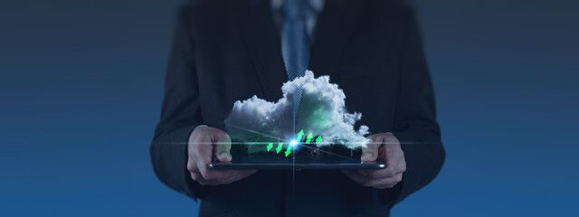 A businessman in a suit holds a tablet displaying a cloud with digital data and upward green arrows, symbolizing AI-driven cloud storage and big data analytics. The background is a dark blue gradient