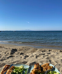 Obraz premium Luxury hotel's beach food snack plates. Sunny day, calm waveless sea, blue sky. Soft brown-gold sand shines on the beach. sea ​​waves hitting the seashore. clear, clean sea water. Balıkesir in Turkiye