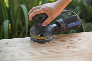 Grinding with an electric wood grinder, restoration of solid wood furniture. Woodwork. Close up of...