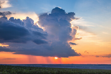 Heavy dark clouds at sunset cover the sun over the fields in Ukraine