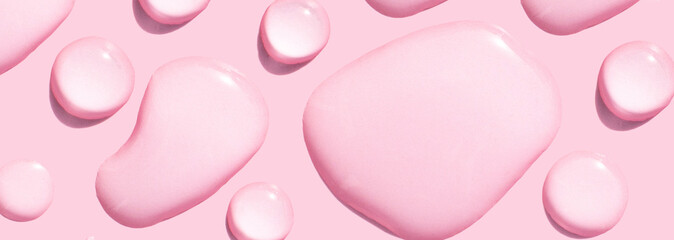 round drops of transparent gel serum on pink background