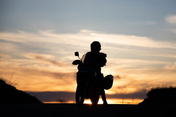 Silhouette of rider on a motorbike admiring sunset - space for your text