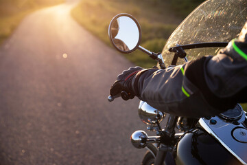 Close-up on the hand of a motorcycle rider in the sunset.