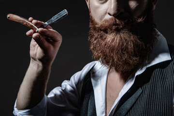 Modern barbershop haircut. Bearded hipster barber isolated on black. Man beard haircut by hairdresser at barbershop. Handsome barber using retro blade while cutting hair. Cropped view
