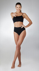 Obraz premium Fitness, portrait and happy woman in underwear pointing at you in studio for weight loss challenge, diet or invite on gray background. Wellness, body and model for motivation, confidence or gesture