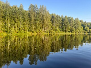 beautiful lake on the shore forest with reflection in water blue sky in reflection of water.