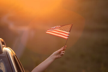 Woma in the car holding a waving american USA flag.