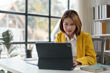 Attractive Asian business woman Use laptop to view computer and talk on mobile phone, contact financial business online. Conduct discussions and contact customers startup business idea.