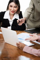 Happy multiethnic business women working together online on a laptop in corporate office.