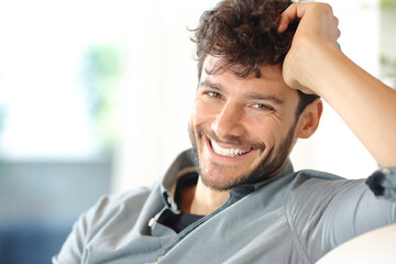 Happy man with perfect smile looks at camera at home