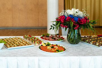 Banquette table setting. Delicatessen appetizers on long banquette table. Colorful delicious snacks on white covered table. Buffet party. Luxury banquette concept.