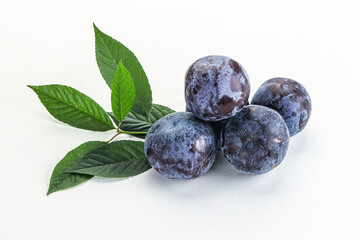Raw purple plums heap with leaves